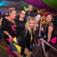 group of friends in 80s outfits and a scary, bloody clown outfit under tent during Wyandotte's 80s vs 90s Halloween Pub Crawl