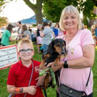 grandmother and grandson holding a brown and black wiener dog