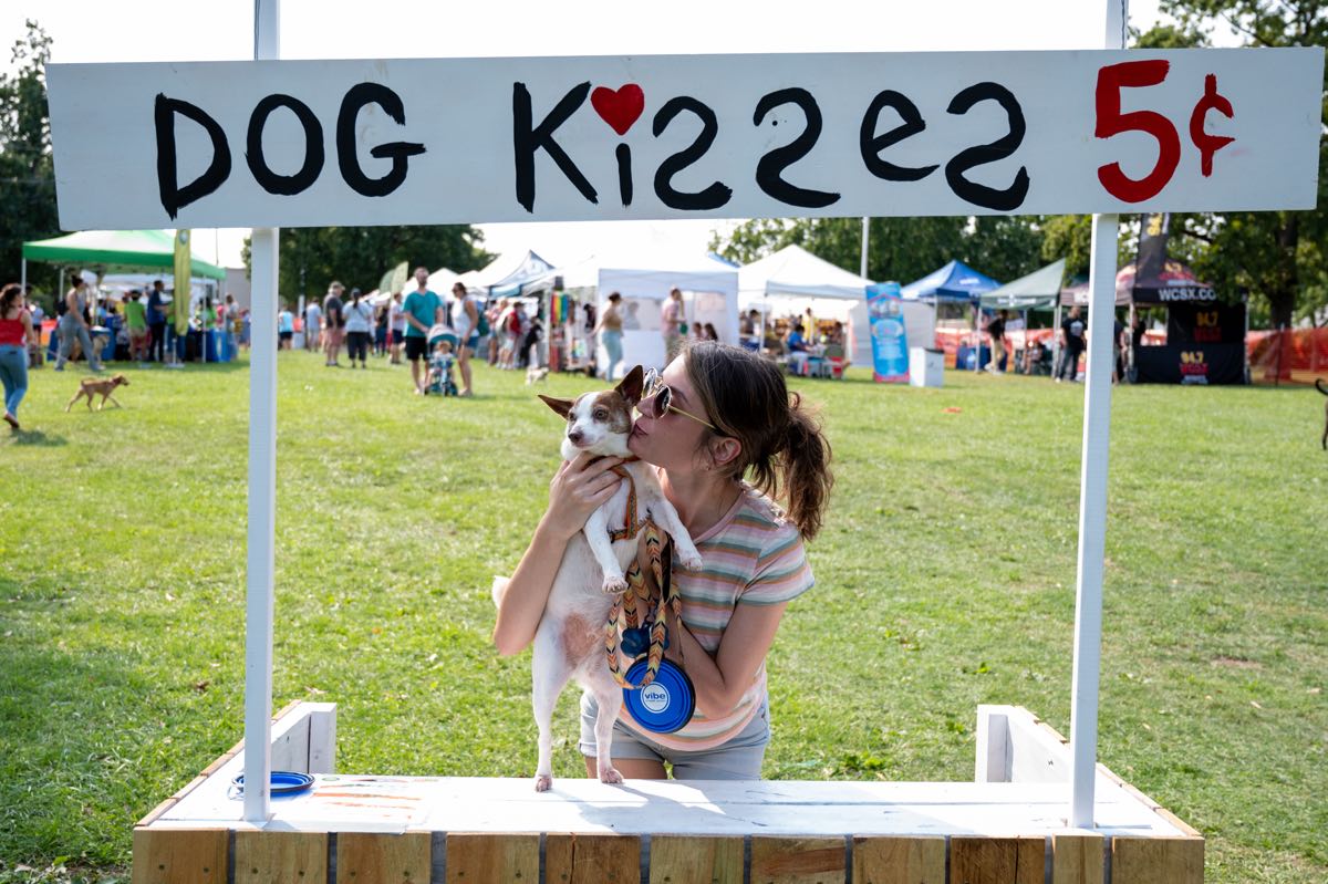 woman kissing her small dog at Dog Kisses booth at Royal Oak's Barktoberfest