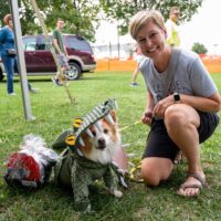 woman smiling at camera with dog dressed as an alligator at Royal Oak's Barktoberfest