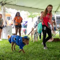 young woman holding leash of dog dressed as police man at Royal Oak's Barktoberfest