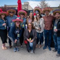 group of friends gathered and posing for the camera, smiling with sombreros and Mexican beer cans