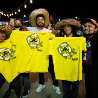 5 friends posing and smiling at the camera, wearing sombreros and holding up yellow Pacifico beer shirts