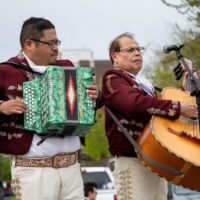 2 men in traditional Mexican garb, one playing an accordion and other playing a large guitar