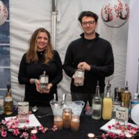 two vendors holding Japanese themes liquor bottles at booth during Wyandotte's Detroit River Cocktail Showdown