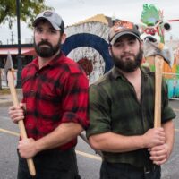 two lumberjack looking men holding axes and posing for camera during Wyandotte's Fire & Flannel Festival
