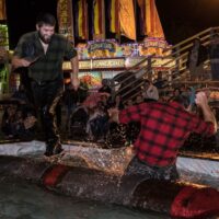 two men attempting log rolling in front of crowd during Wyandotte's Fire & Flannel Festival