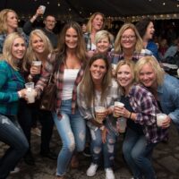 group of ladies in flannel shirts with beer cups posing for camera during Wyandotte's Fire & Flannel Festival