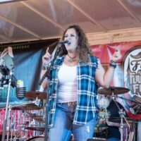 woman signer in blue flannel vest on stage during Wyandotte's Fire & Flannel Festival