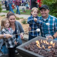 parent, boy, and girl roasting marshmallows during Wyandotte's Fire & Flannel Festival