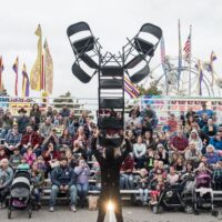 man balancing tall stack of chairs on face in front of crowd during Wyandotte's Fire & Flannel Festival