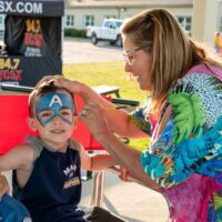 woman paining Captain America mask on young boy at Riverview Summerfest