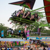 three young ladies posing for camera while riding cliff hanger ride at Riverview Summerfest