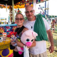 couple posing with new stuffed animals after winning water squirter game at Riverview Summerfest