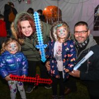 parents with two daughters wearing face paint holding play swords during Wyandotte's Rockin' NYE