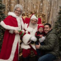 dad and toddler posing with Santa & Mrs. Claus at Royal Oak Jingle