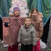 three kids, one in present costume, smiling for camera at Royal Oak Jingle