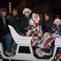 two families with parents and kids with blankets sitting in a white carriage during Royal Oak Jingle