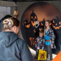 three kids posing in front of Halloween display background during Royal Oak Spooktacular
