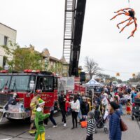 view of crowd with Fire Truck displaying giant spider during Royal Oak Spooktacular