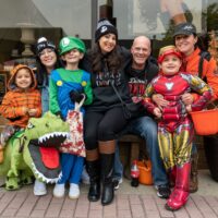 parents with three kids in halloween costumes; kid riding dino, Luigi, and Iron Man during Royal Oak Spooktacular