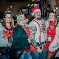 four friends in silly, fun Christmas outfits at bar during Wyandotte's Santa Pub Crawl