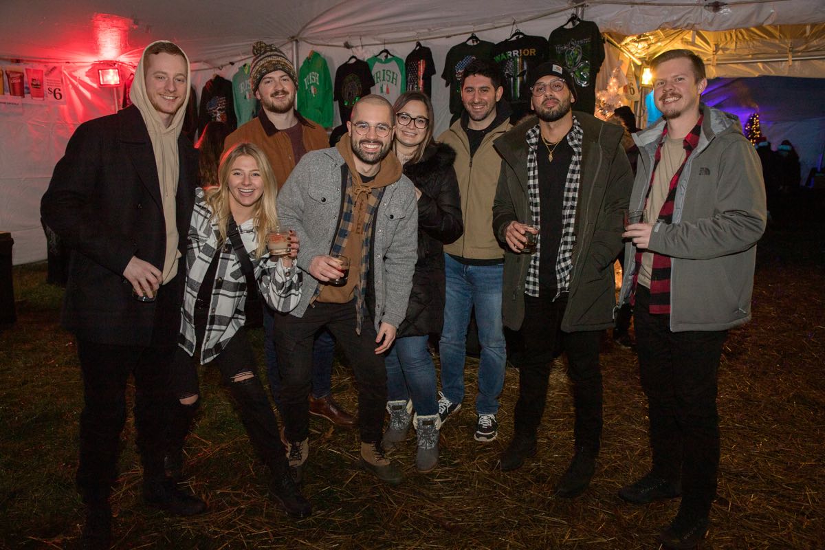 group of friends in coats holding glasses under white tent at Wyandotte's Winter Beer Cocktail Fest