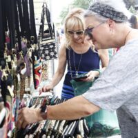 two woman in sunglasses looking at wallets and purses at booth during Wyandotte Art Fair
