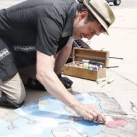 sidewalk chalk artist working on piece at Wyandotte's Street Art Fair