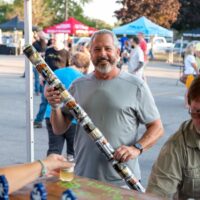 man holding beer can "staff" at beer tent during Wyandotte's Beer Fest