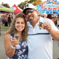 couple holding up beer sampler glasses and posing for camera during Wyandotte's Beer Fest