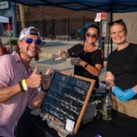 man giving thumbs up with waiting for wine pour at booth during Wyandotte's Wine Crawl