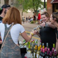 two lady vendors pouring wine for event goers during Wyandotte's Wine Crawl