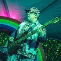 band bass player on stage in front of rainbow backdrop