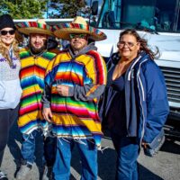 two men wearing sombreros and ponchos and two woman all smiling at the camera