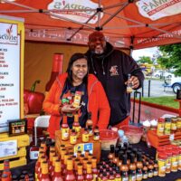 couple displaying their hot sauces in a vendor tent