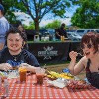 couple eating bbq at a table with a checkered table cloth