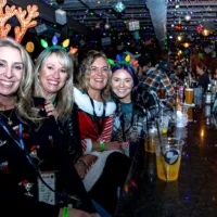 Four ladies at a bar wearing Holiday gear smiling and posing.